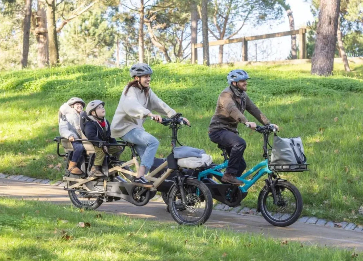 Family riding premium cargo electric bikes with children on a bike path