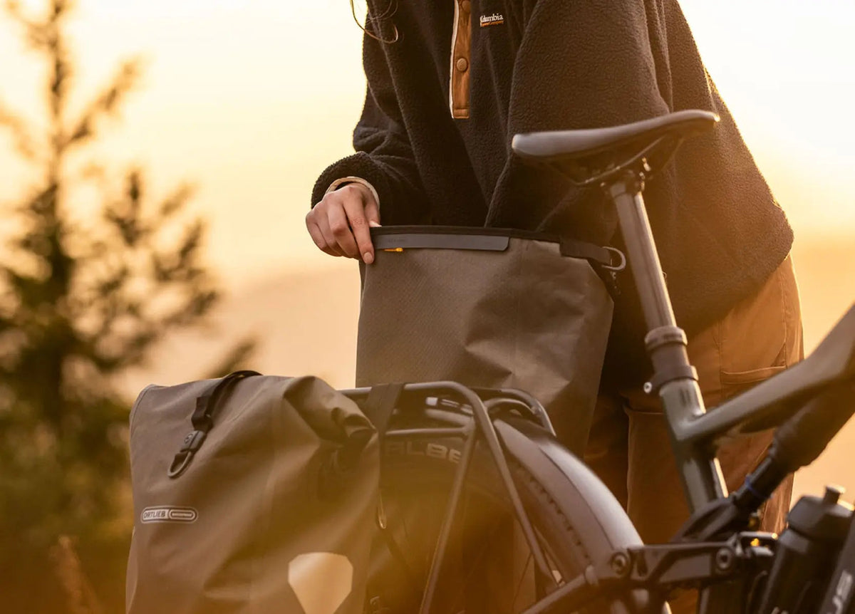Sam from Electric Bikes Brisbane with her pannier bag opened and trail kit laid out — lock, Lezyne multi-tool, Velox sealant, spare tube and mini pump