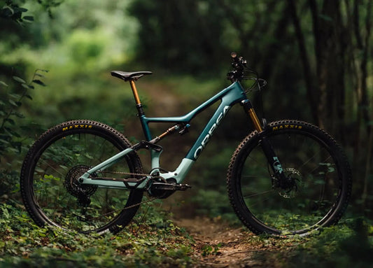 Orbea Rise lightweight full suspension electric mountain bike on a forest trail