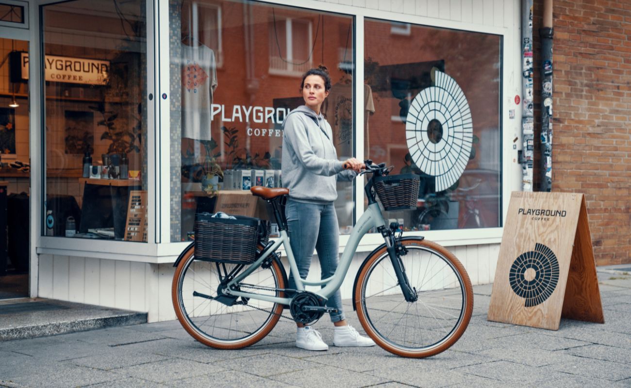 Riese & Müller Swing5 Silent step-through E-Bike with baskets outside city cafe