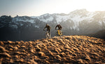 Two Orbea eMTB riders on alpine mountain trail with snow-covered peaks