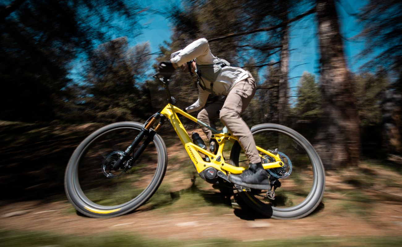 Orbea full-suspension eMTB rider descending fast on forest mountain bike trail