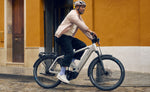 Cyclist riding a Riese & Müller Charger5 electric touring bike on a cobblestone street