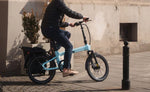 Person riding a turquoise electric bike in an urban setting | Electric Bikes Brisbane
