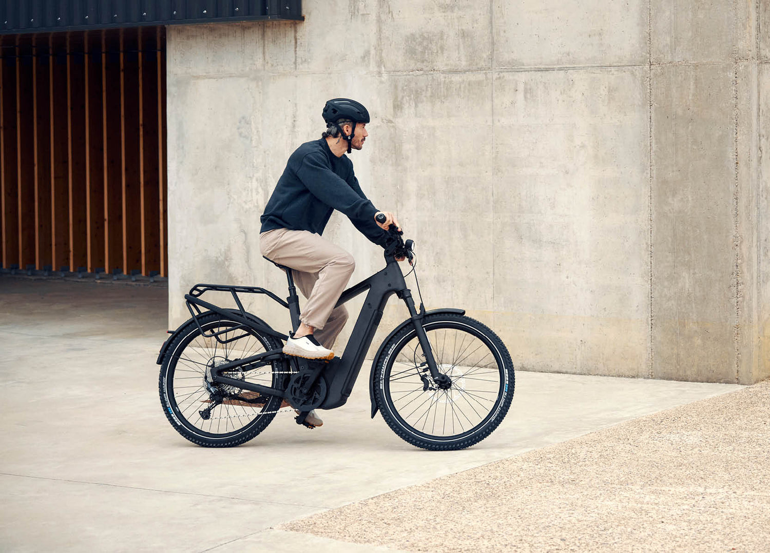 Man riding a Riese & Muller Delite5 electric bike with a concrete wall as background