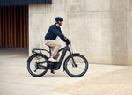 Man riding a Riese & Muller Delite5 electric bike with a concrete wall as background