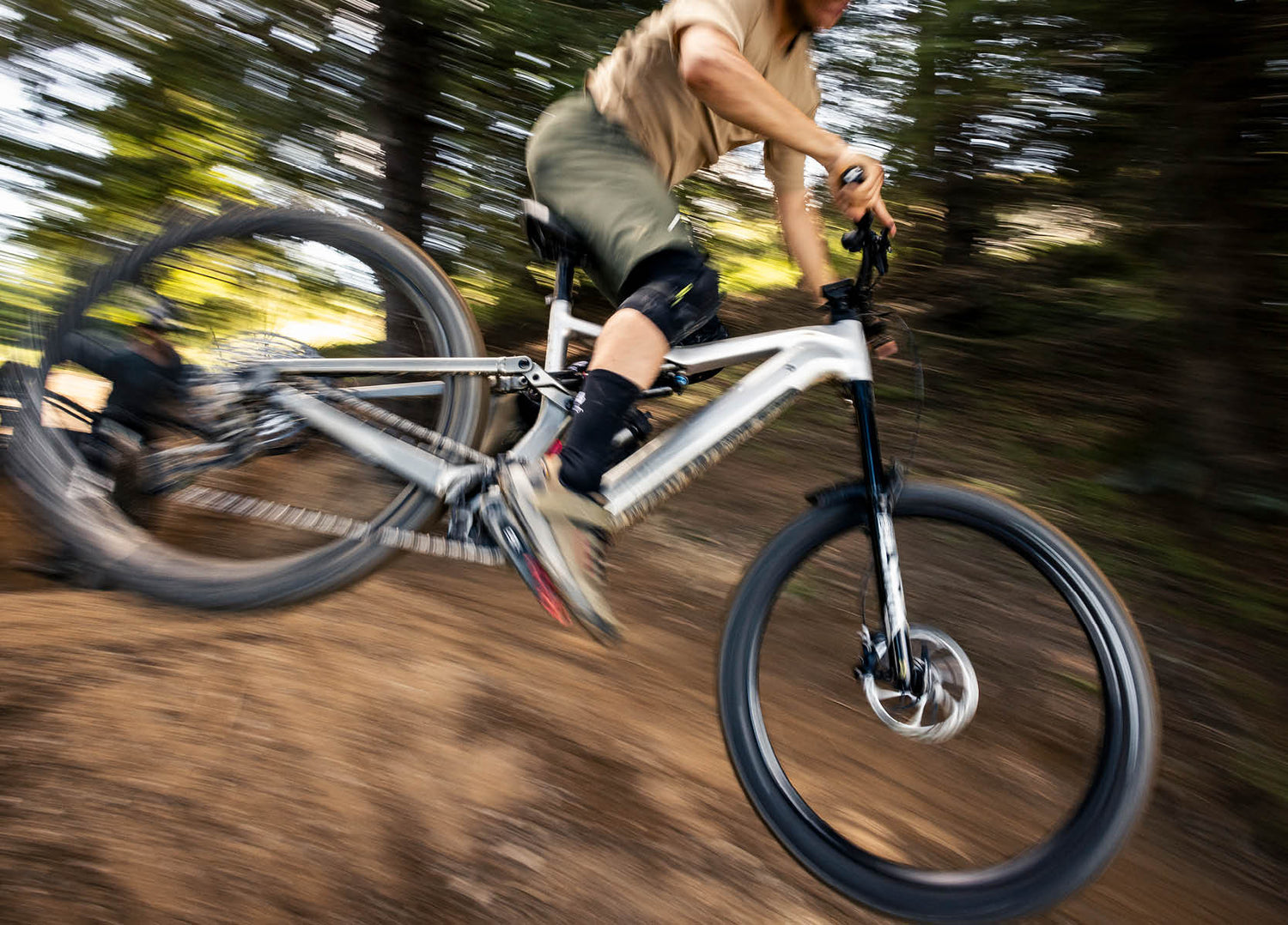 Person riding the 2026 Focus Jam2 electric mountain bike fast down a trail over a jump