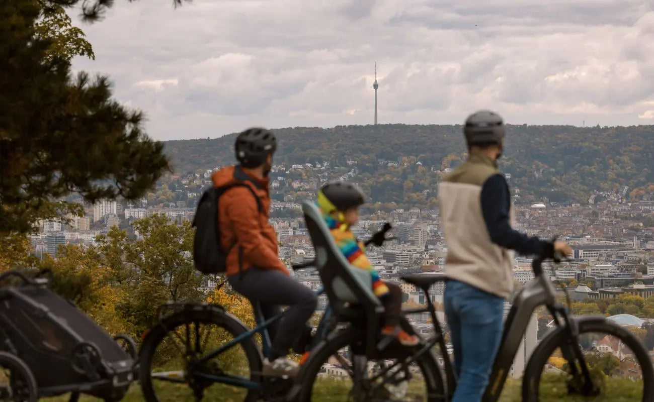 Two adults and a child on Focus F26 Aventura2 6.7 Wave E-Bike with a scenic city view in the background | Electric Bikes Brisbane
