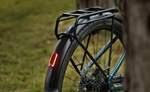 Focus F26 Aventura2 6.8 800Wh E-Bike wheel with a black rack and red reflector on a blurred natural background