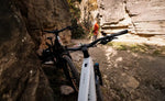Focus F26 Jarifa2 6.7 Hardtail E-MTB, Silver leaning against a rock wall with a person in the background on a trail. | Electric Bikes Brisbane