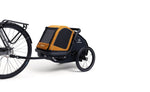 Orange and black Hamax Milou dog trailer connected to a bicycle’s rear axle using the bike arm and hitch.