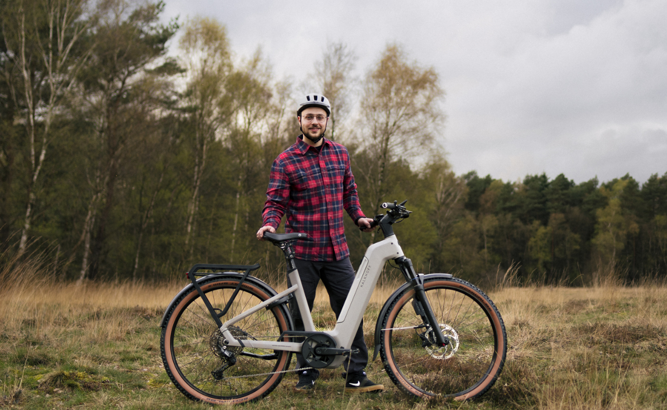 Man standing with a Kalkhoff K26 Entice 5+ Move Wave EBike, Moonstonegrey in a forested area