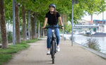 Person riding a Moustache Open Xroad 2 eBike 2026 on a path by a river with trees in the background | Electric Bikes Brisbane