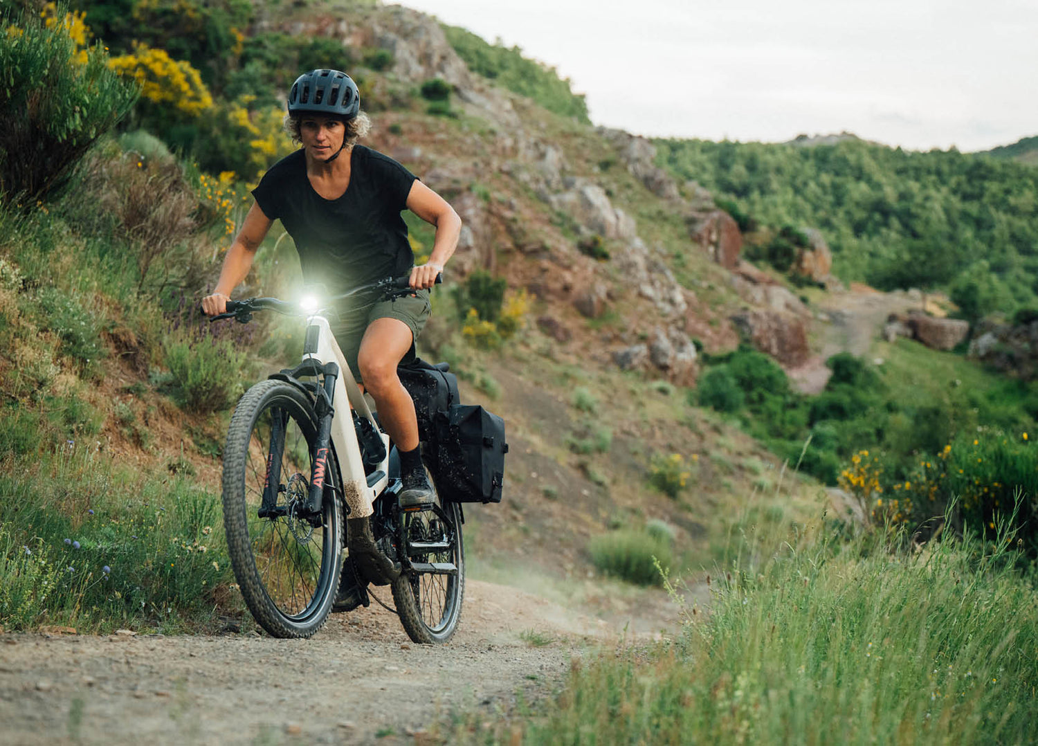 Lady riding an Orbea Muga electric bike climbing on a gravel trail 