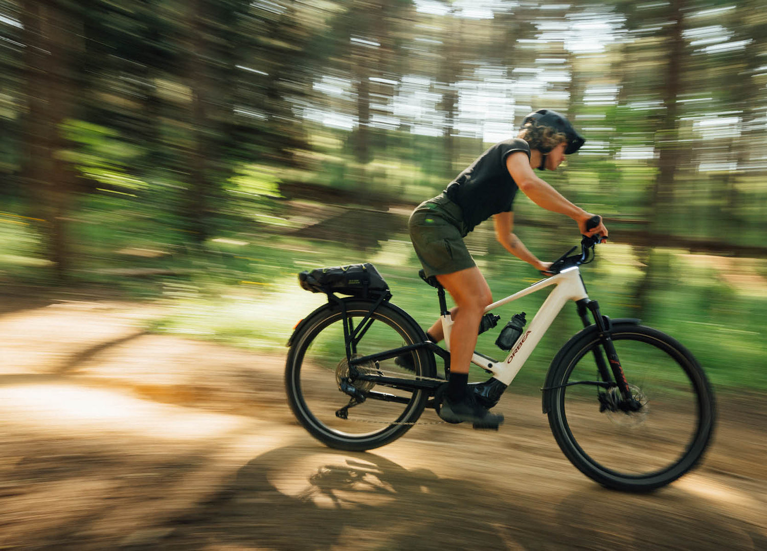 Lady riding an Orbea Muga electric bike on a forest path with blurred background