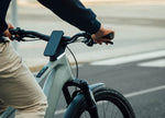 Man riding an Orbea Muga electric bike on a road with smartphone mounted centrally