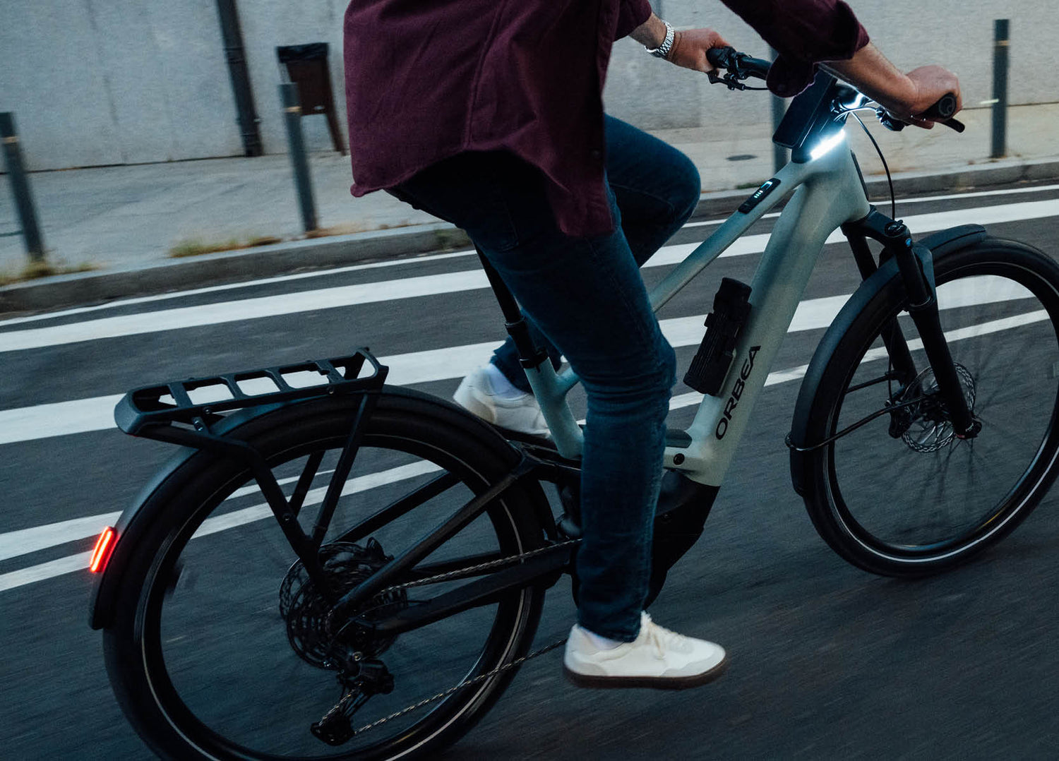 Person riding an Orbea Muga electric bike on a dark city street using the daylight running and bright headlight