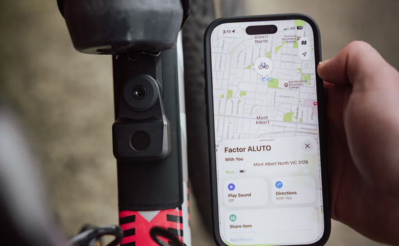 iPhone displaying the bike’s location in Apple Find My beside a frame-mounted Quad Lock Bike Alarm and Finder.