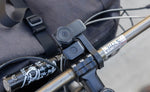 Quad Lock Bike Alarm and Finder fitted beneath a Quad Lock phone mount on a bicycle handlebar.