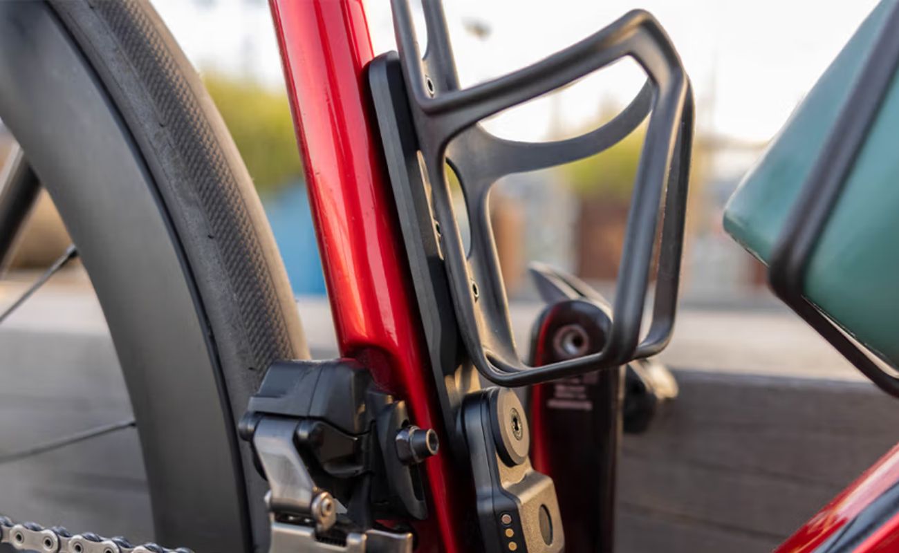 Quad Lock Bottle Cage Adaptor fitted to a red bike frame with a black bottle cage and Bike Alarm and Finder mounted below.