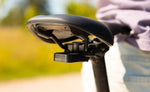 Quad Lock Saddle Rail Adaptor holding a Bike Alarm and Finder beneath a black bicycle saddle.