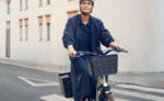 Rider on a Riese & Müller Swing5 electric bike with optional front and rear baskets on an urban street