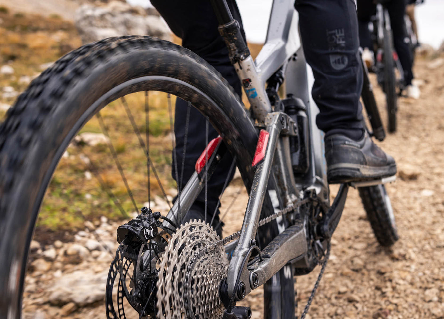 Close-up of th erear lights and drivetrain of a F26 Focus Thron2 6.8 ABS ebike climbing a wet, rocky trail 